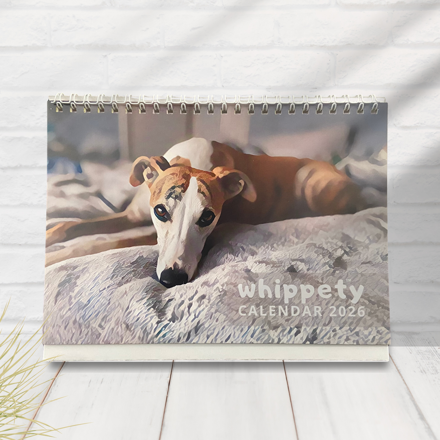 Small calendar with a whippet dog on the cover, displayed on a wooden surface.