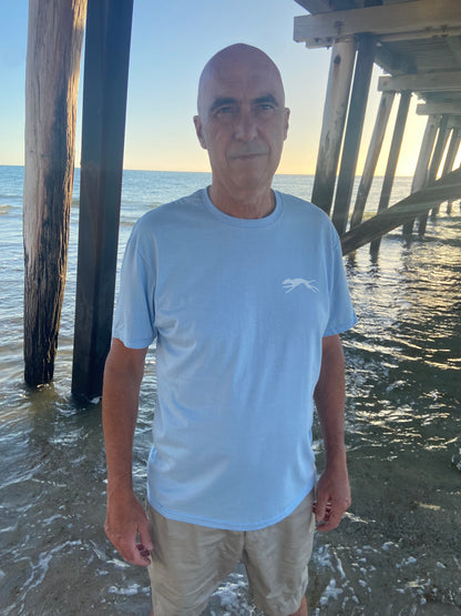 Man standing by sea wearing a blue t  shirt and beige pants