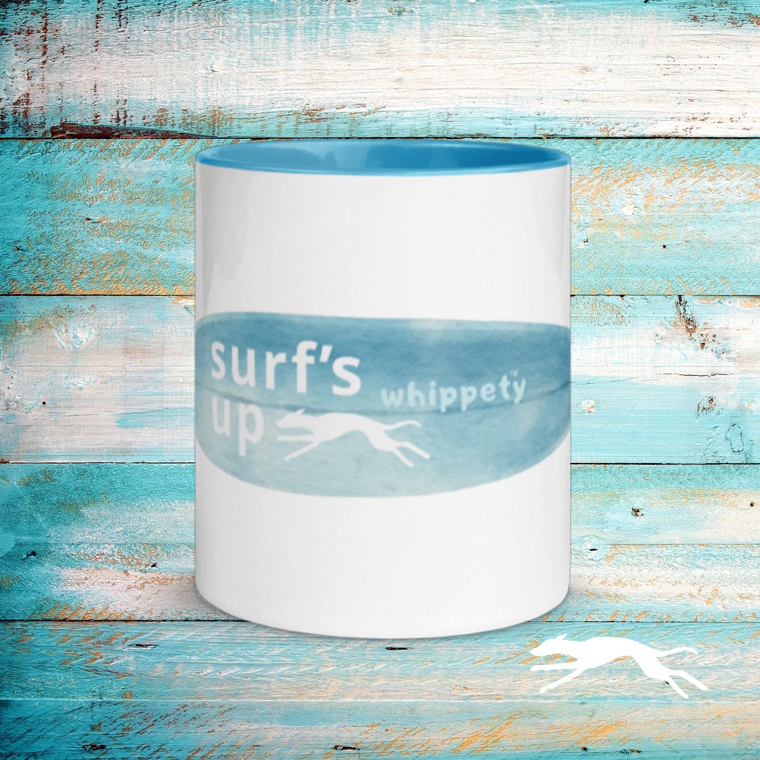 White mug with blue interior and 'surf's up whippety' text on a wooden background