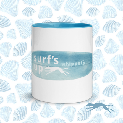 White mug with blue interior and 'surf's up whippety' text on blue shell pattern background