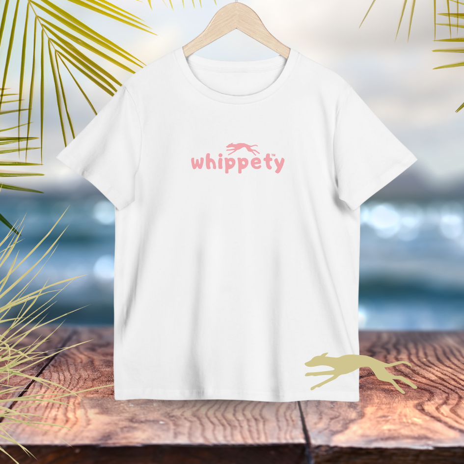 White t-shirt with pink 'whippety' logo on a wooden surface with beach background